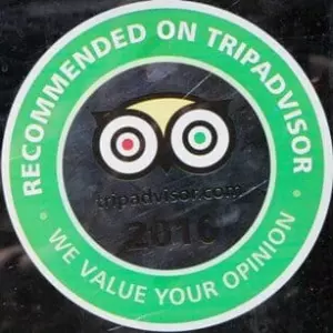 A green circular sticker with the text "RECOMMENDED ON TRIPADVISOR" around the border. The center features the TripAdvisor owl logo with red and green eyes, the TripAdvisor website URL, and the year "2016" below. The bottom banner says "WE VALUE YOUR OPINION".