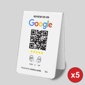 A 5 Google Tap or Scan Table Tents on a gray surface displays "Review us on Google" with a QR code and five stars below it. The card instructs users to tap or scan the QR code to leave a review. Powered by review.cards, it features a red "x5" icon in the bottom right corner.