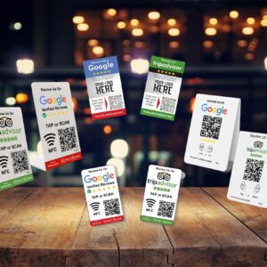A collection of Hospitality Bundle 1 from TripAdvisor, featuring QR codes and NFC tags for reviews. The cards are displayed on a wooden surface with a blurred background of warm lights, creating a cozy ambiance.